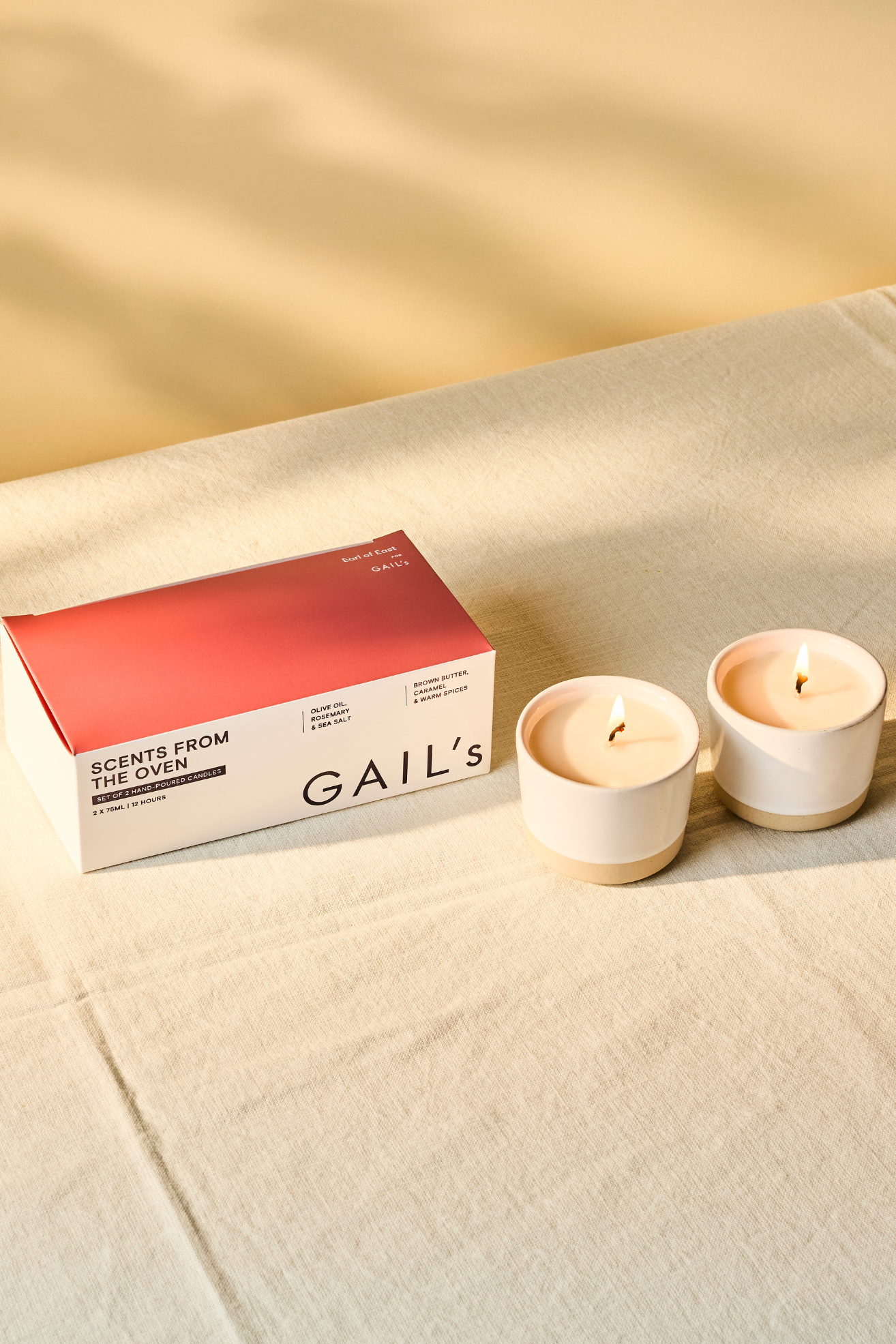 A pair of white ceramic candles on a linen tablecloth