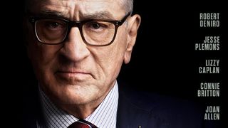 Headshot of Robert De Niro against a black background staring seriously, wearing dark rimmed glasses and a white shirt with a blue check and maroon tie. 