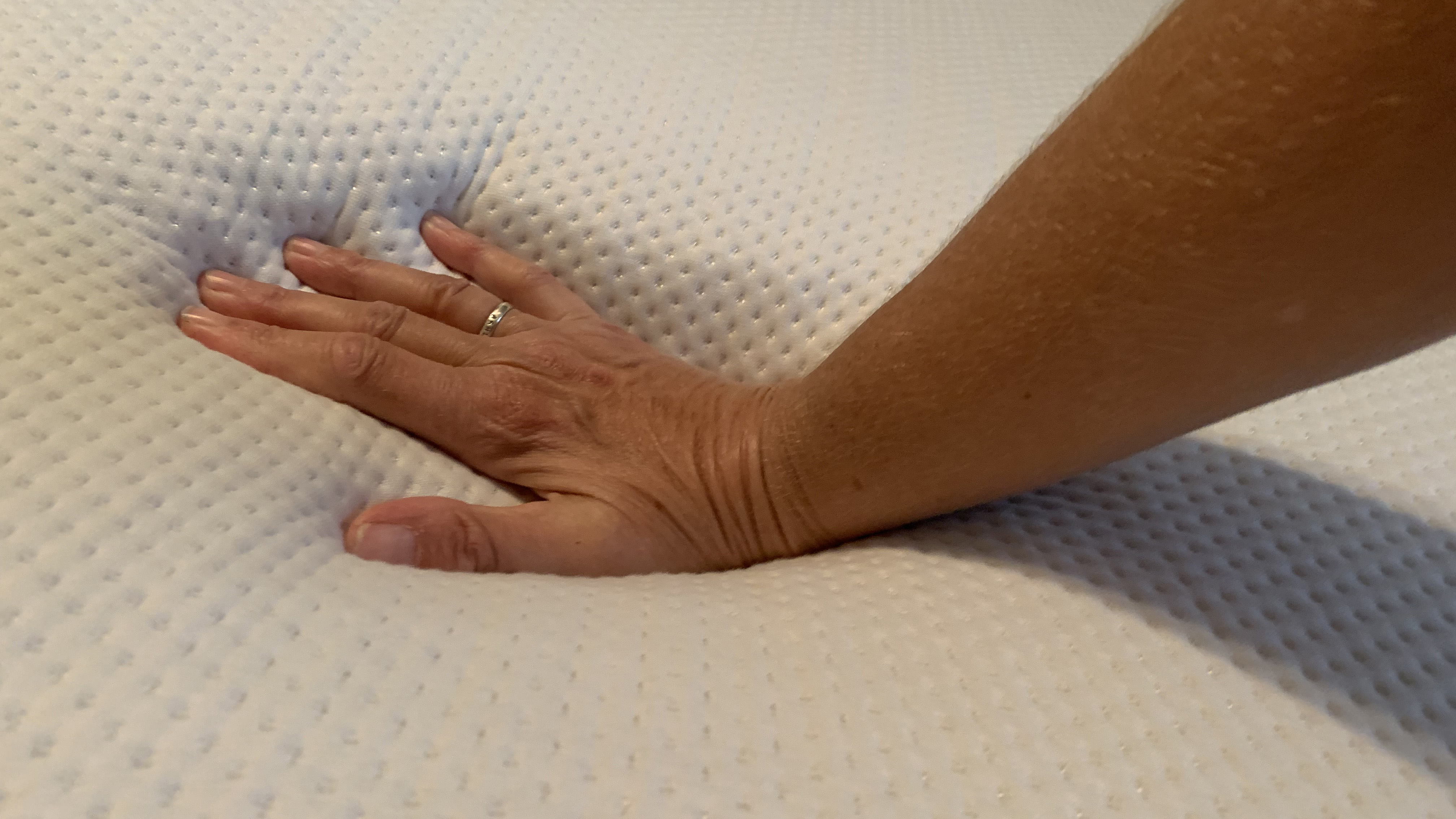Our reviewer places her hand on the top of the Purple Plus Mattress to see how cool to the touch it feels