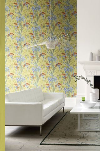 Living room with white couch, yellow floral print wallpaper and geometric print rug