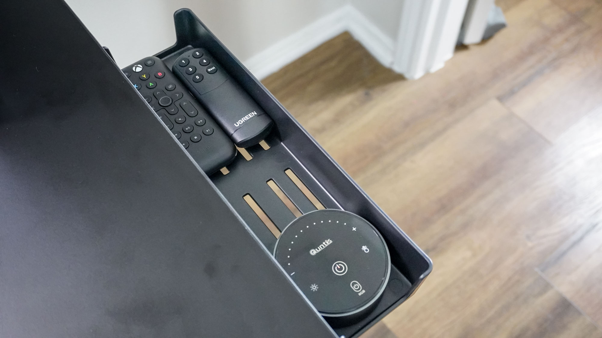 Several remotes placed inside the storage tray that comes with the Corsair Platform:4 Elevate Desk