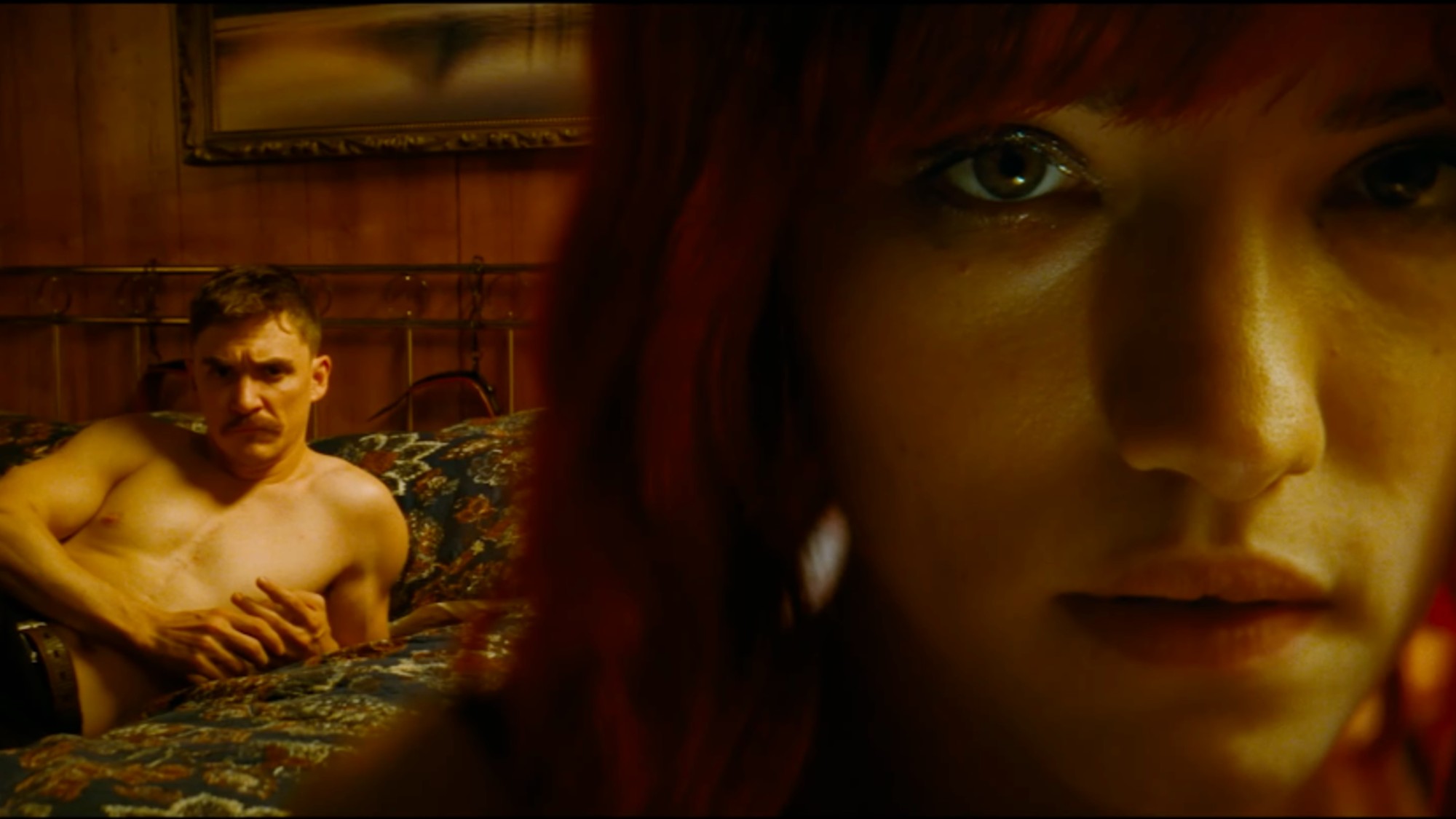 An extreme close up of Willa Fitzgerald with a shirtless man behind her in bed in Strange Darling