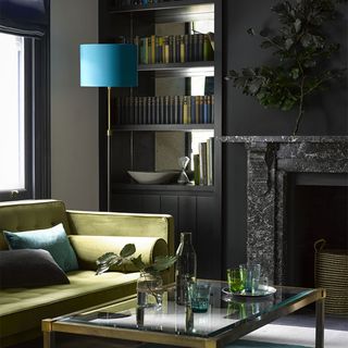 Dark living room with green sofa and mirrored alcoves
