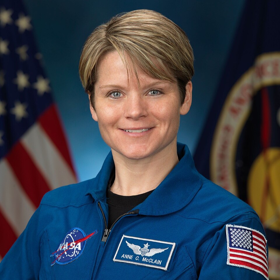an astronaut in blue jumpsuit is smiling.