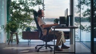 A tight shot showing a man sitting at the Fractal Refine gaming chair in front of a desk