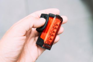 A white hand holds a large red bike light