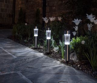 Cambridge Solar Stake Lights in a garden bed, with a stone path