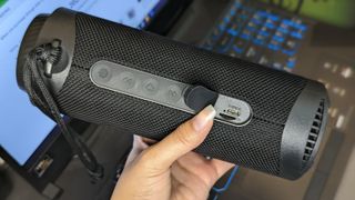 Tronsmart T7 portable Bluetooth speaker held in hand with charging port exposed