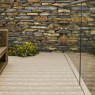 Wooden decking in front of stone wall next to mirror