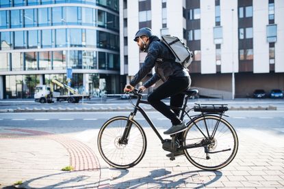 Male cyclist commuting in the city, wearing a backpack for cycling