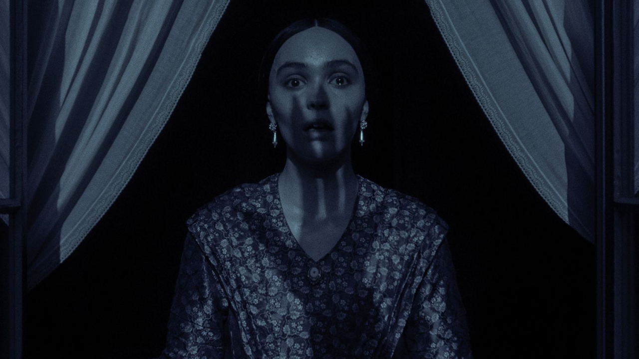 En kvinna ser rädd ut när skuggan av Nosferatus hand visas på hennes ansikte i Nosferatu (2024)