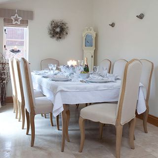 dinning room with white wall wooden dinning table and chairs and wreath on wall