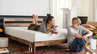 A couple setting up their new Tuft & Needle Mattress with a glass of wine in hand