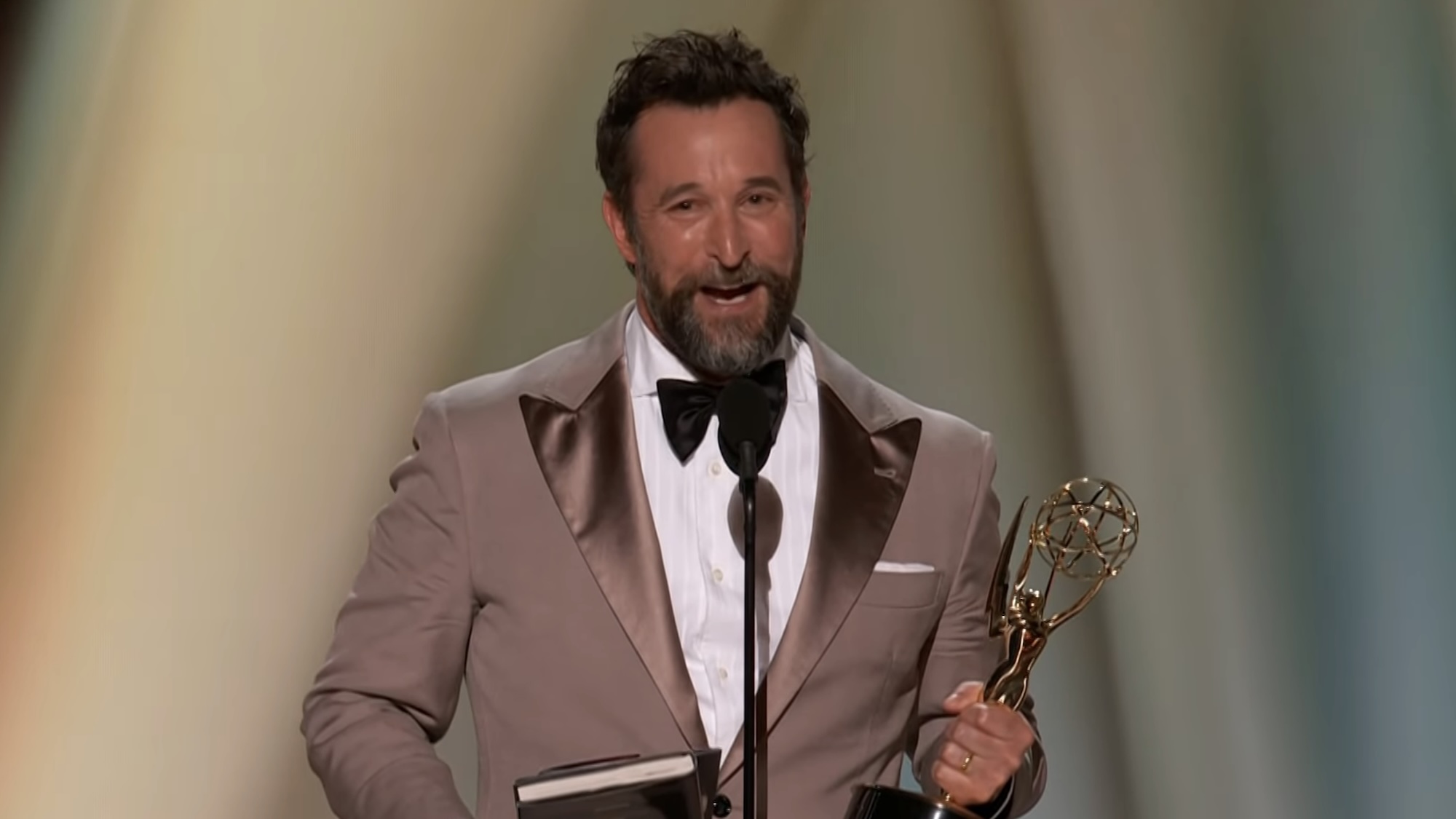 Noah Wyle accepting 2026 Emmy for The Pitt while holding trophy and library book