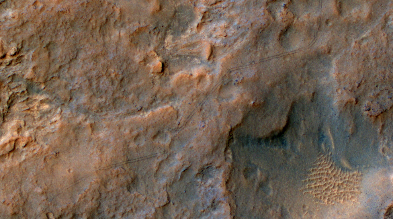 Two parallel tracks left by the- wheels of NASA's Curiosity Mars rover cross rugged ground in this portion of a Dec. 11, 2013, observation by the High Resolution Imaging Science Experiment (HiRISE) camera on NASA's Mars Reconnaissance Orbiter. The rover itself does not appear in this part of the HiRISE observation. Image released Jan. 9, 2014