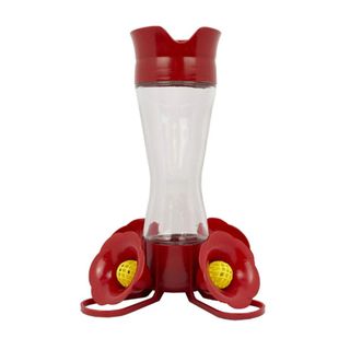 A dark red hummingbird feeder with a clear base, red lid, and red and yellow flower decorations at the bottom