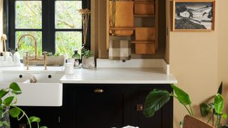 a black kitchen with a white countertop and beige walls, with decor and plants around