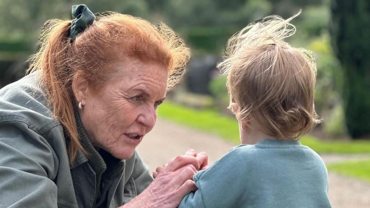 Sarah Ferguson wearing a green jacket kneeling down on a garden path talking to Ernest Brooksbank