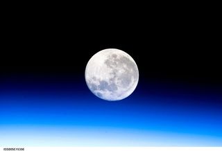 A full moon is visible in this view above Earth's horizon and airglow, photographed by Expedition 10 Commander Leroy Chiao on the International Space Station.