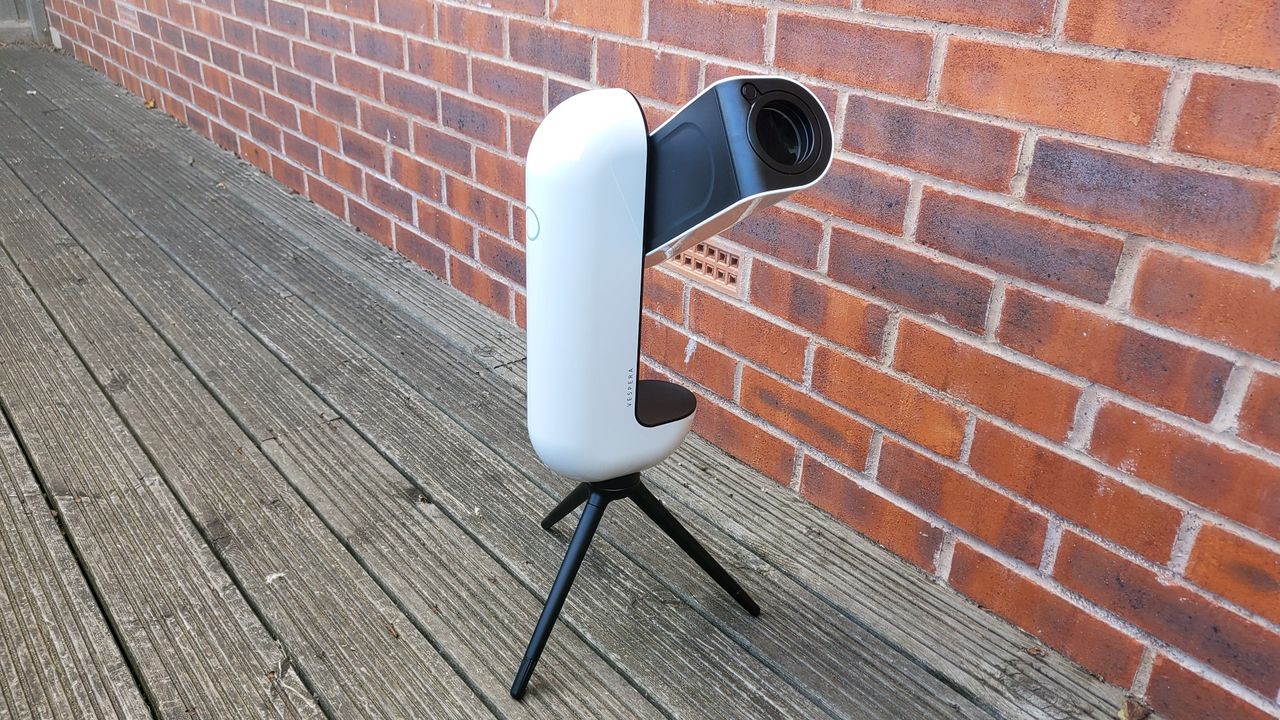 Image of the Vaonis Vespera Observation Station. It's a sleek white capsule balanced on a black tripod. It's facing to the left, with the telescope/camera arm is, pointing towards us.