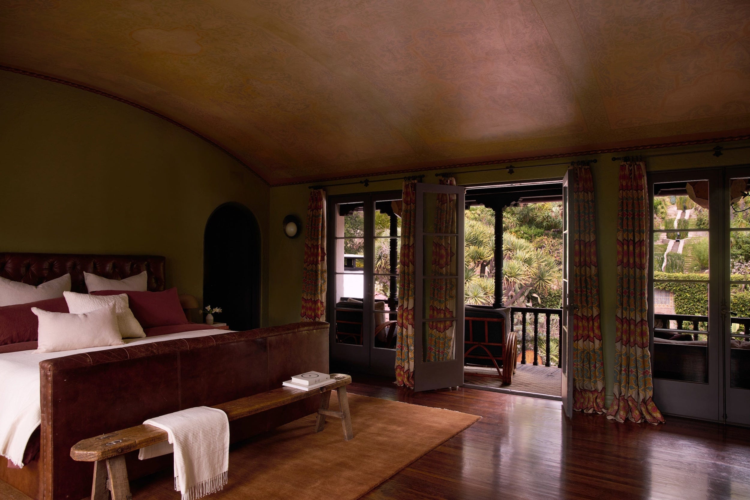 green bedroom with painted ceiling and three french doors leading to balcony