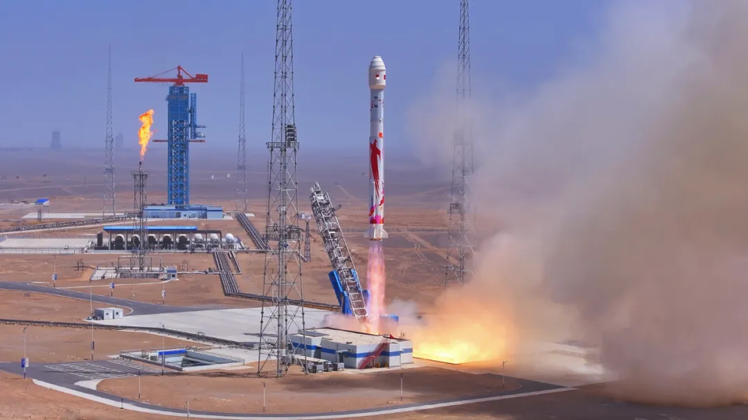 A rocket blasts off against a grey-blue sky