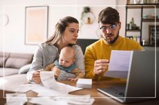 worried couple with a baby at home looking at bills