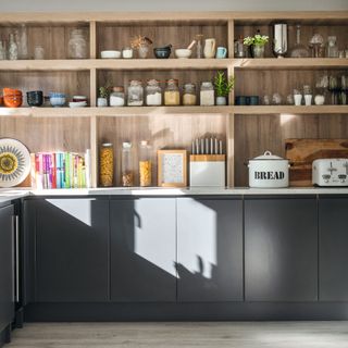 Fitted kitchen with a wall of storage shelves and dark grey units
