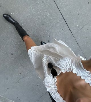 Woman wearing white dress and black calf boots.