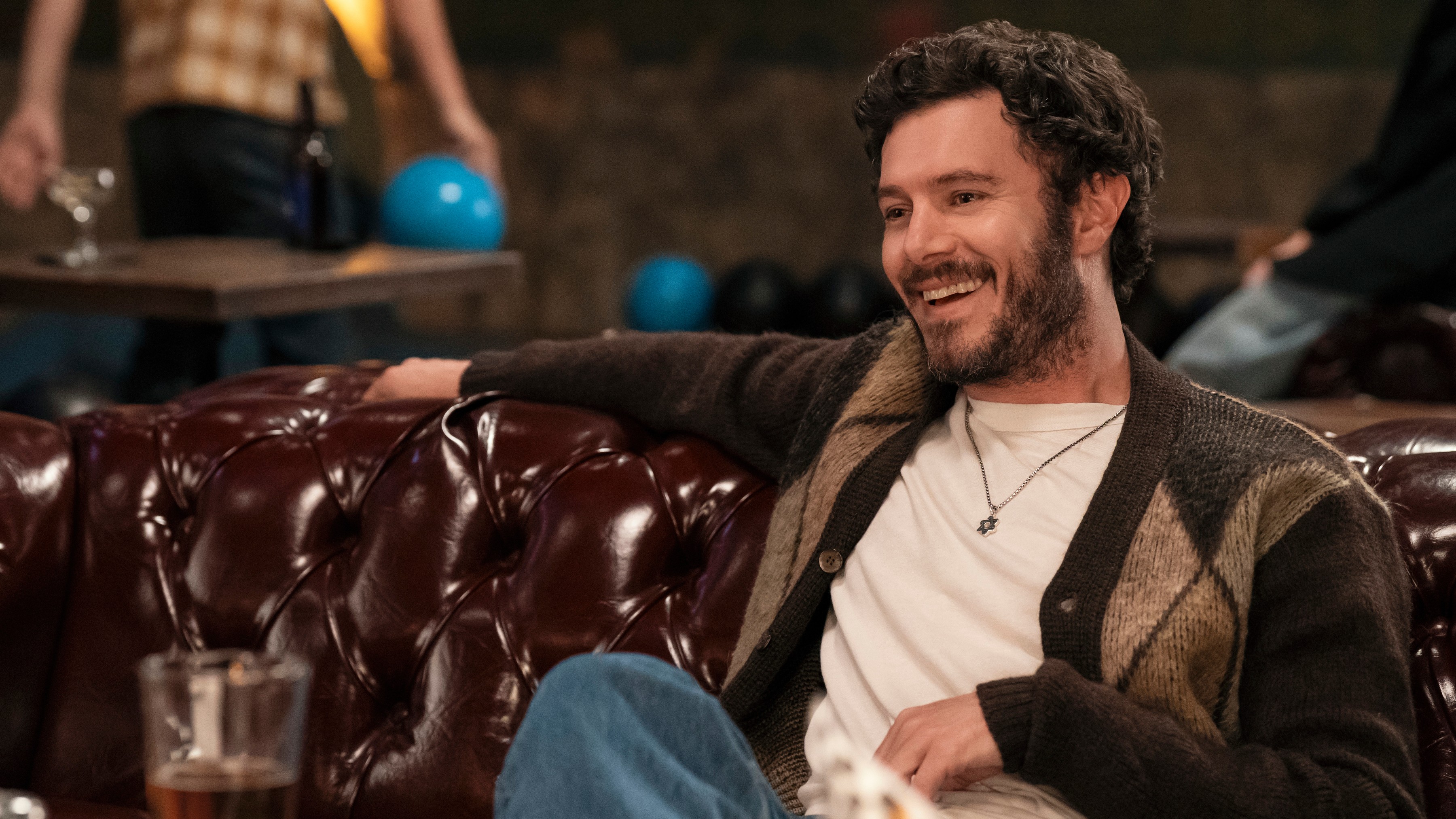 Noah (Adam Brody) sits on a sofa in a scene from "Nobody Wants This" season 2