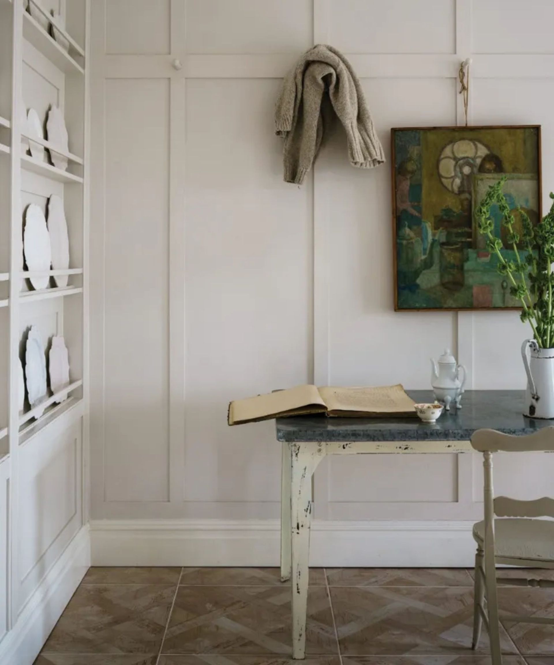 room with white panelled walls, wood floors, rustic desk and artwork on wall