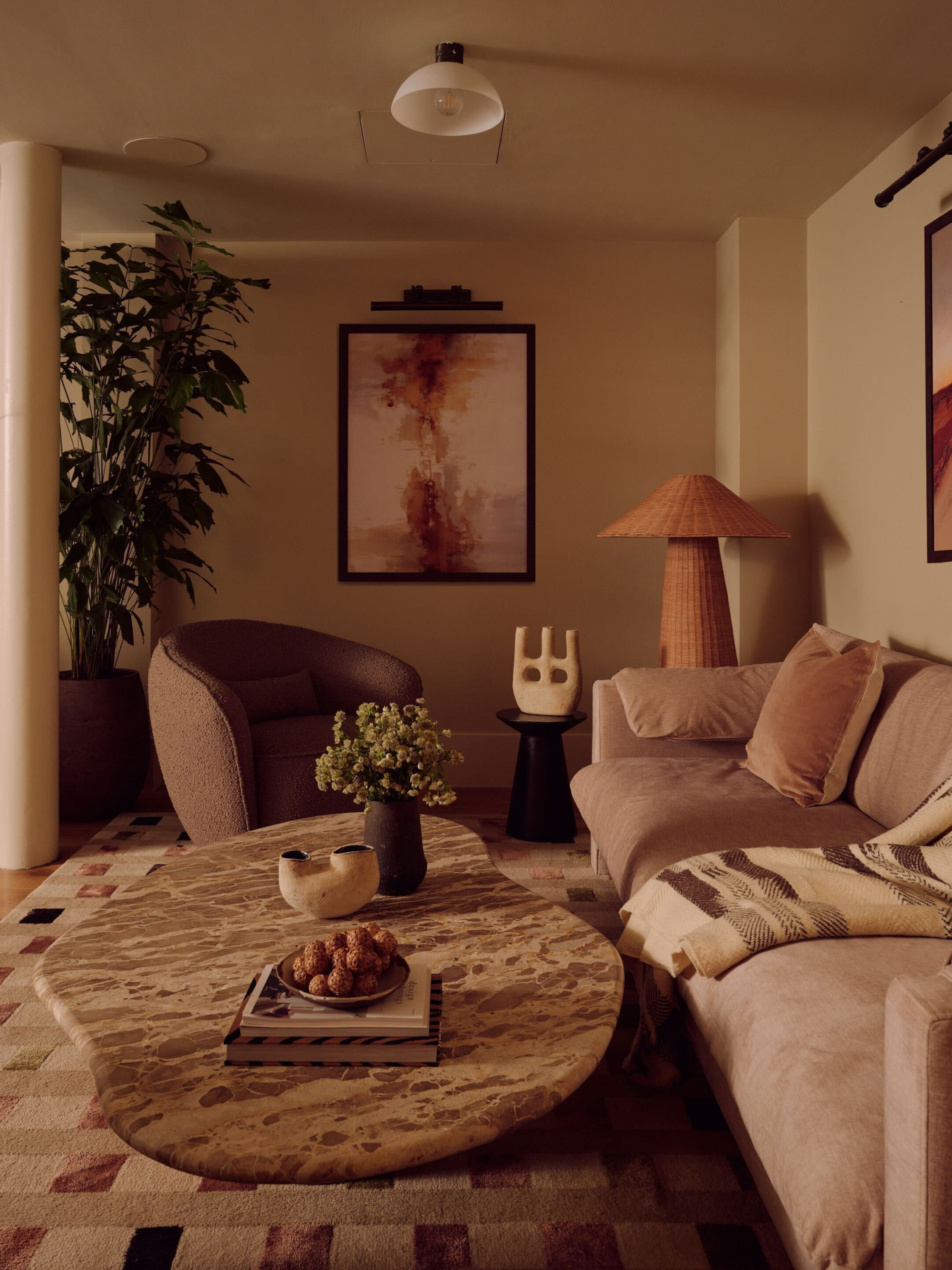 Beige living room with travertine coffee table, pale pink sofa, mole armchair, pink artwork