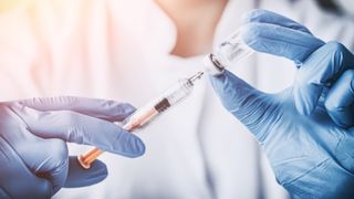 gloved hands preparing vaccine