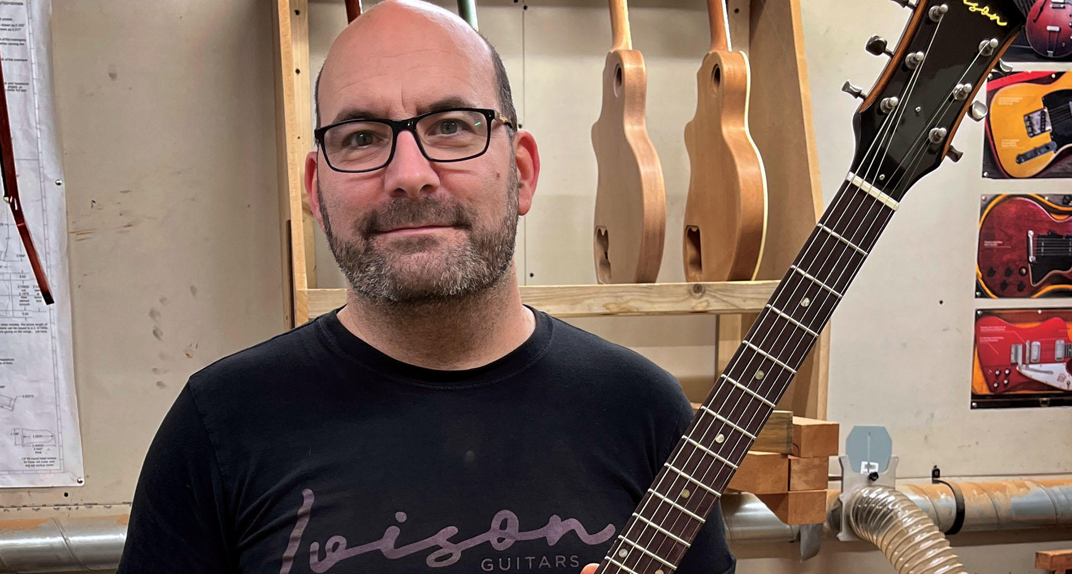 Neil Ivison photographed in his workshop with an Ivison Dakota and his Ivison Guitars T-shirt.