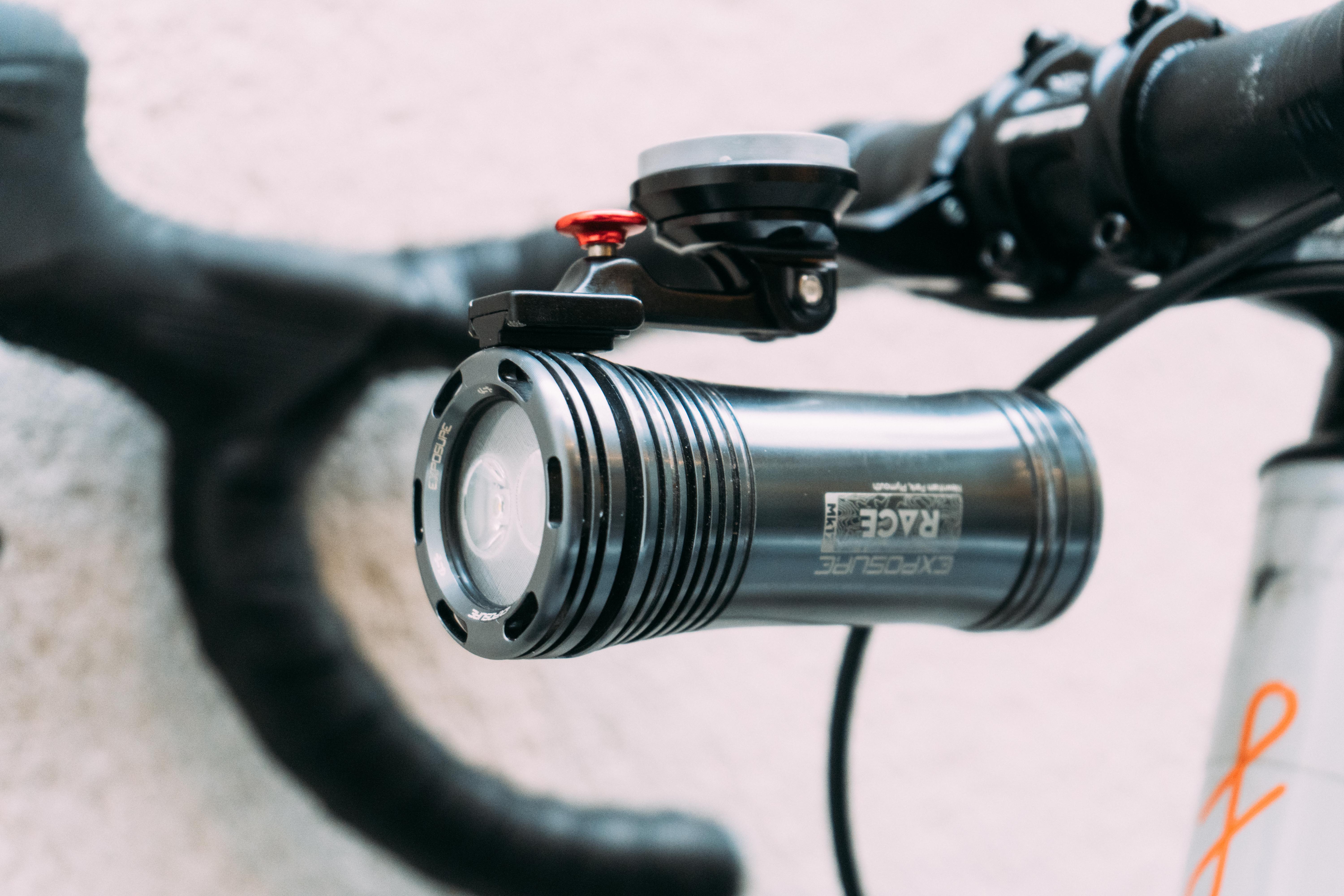 a silver light mounted under a metal bike computer mount