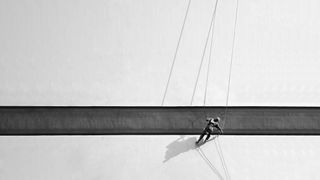 Person rappelling down a building with stark shadows in monochrome