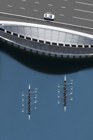 An aerial view of two rowing boats next to a bridge
