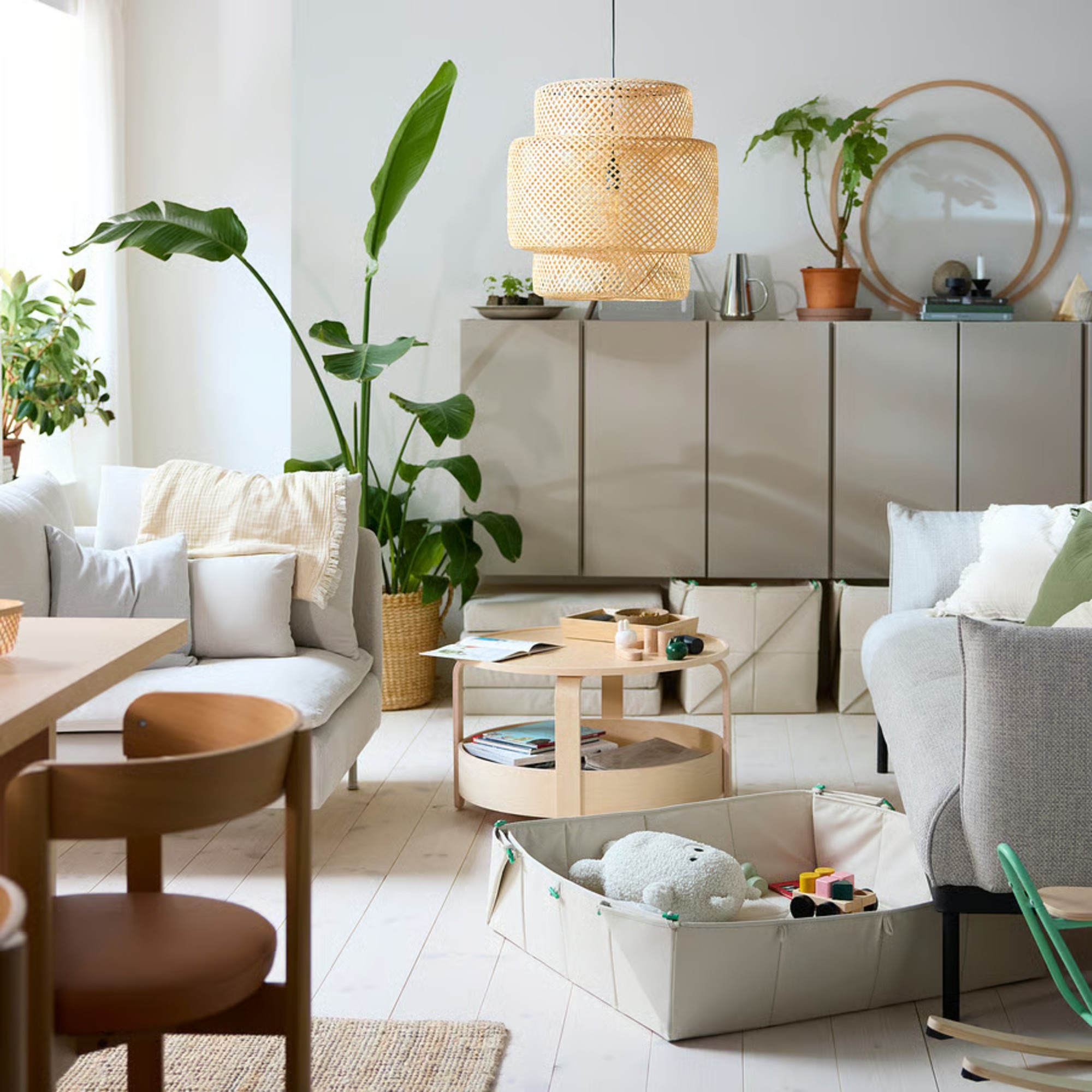 IKEA's GREJSIMOJS foldable toy storage boxes in a living room slotted under a sofa and under a sideboard