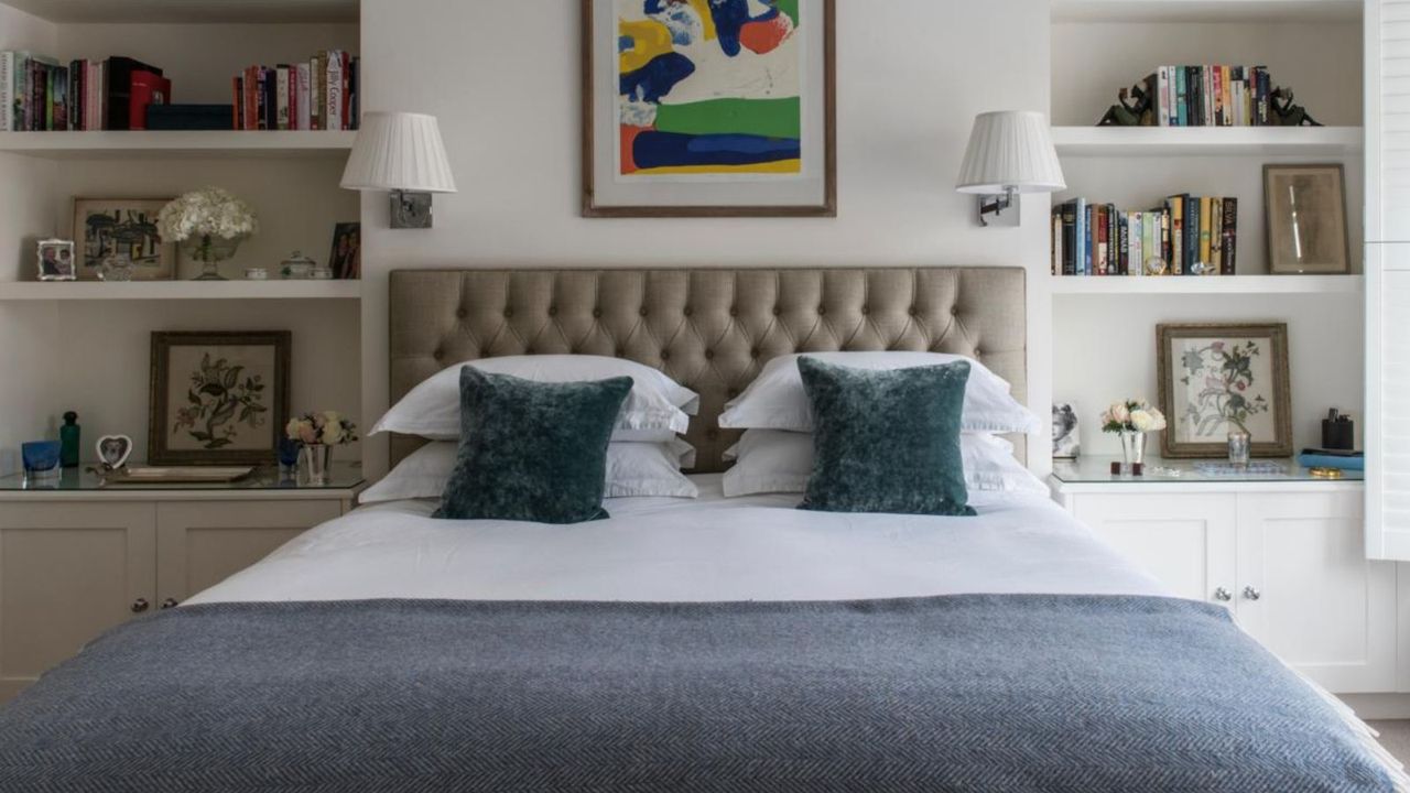 Master bedroom with a double bed and padded headboard. Fitted shelves and window with shutters. Renovated 19th century townhouse and family home in West London, home of Joanna Sharon.