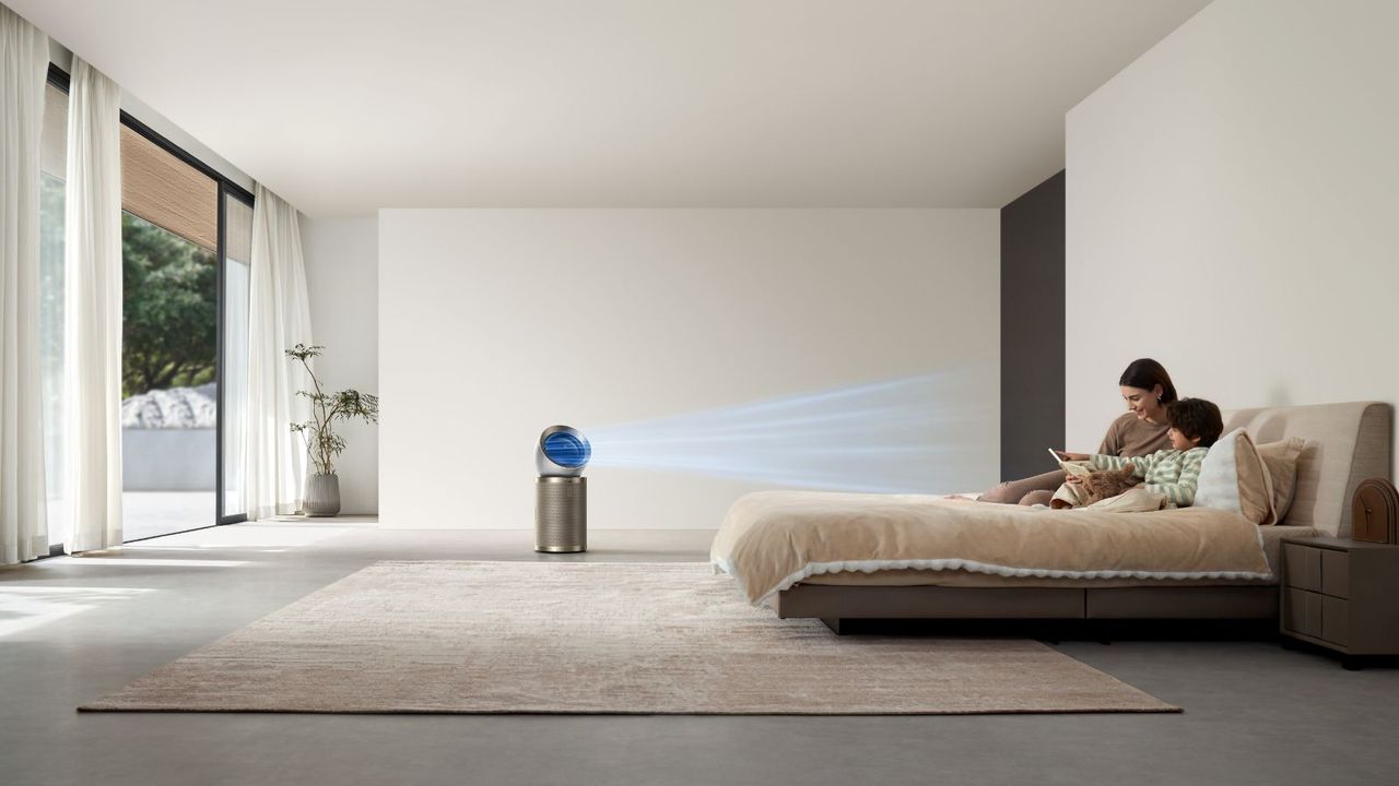 Dreame AirPursue PM20 air purifier in large bedroom emitting blue beams representing airflow, towards bed where mother and child are reading.