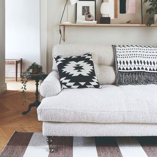 A boucle cream sofa with a striped rug