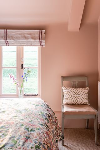 A pink toned bedroom with paint on the walls and ceiling