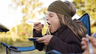 camping tips for kids: kid eating a camping meal