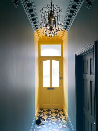 A hallway painted teal with the door in yellow
