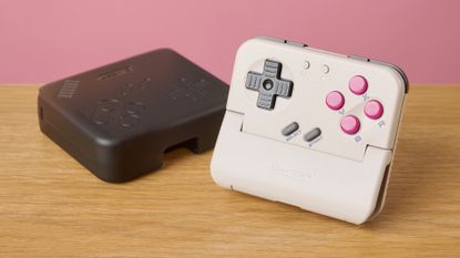 The GameSir Pocket Taco propped up next to its carry case, in front of a pink background.