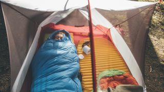 Young woman sleeping in sleeping bag in a tent
