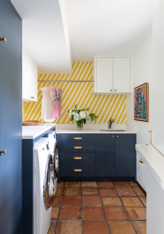 blue laundry room with yellow stripe wallpaper terracotta tiles