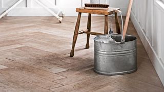 wooden parquet flooring with zinc cleaning bucket and mop