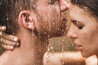 Close up portrait of couple in love kissing under tropical shower with passion. Intimate, togetherness and romantic.