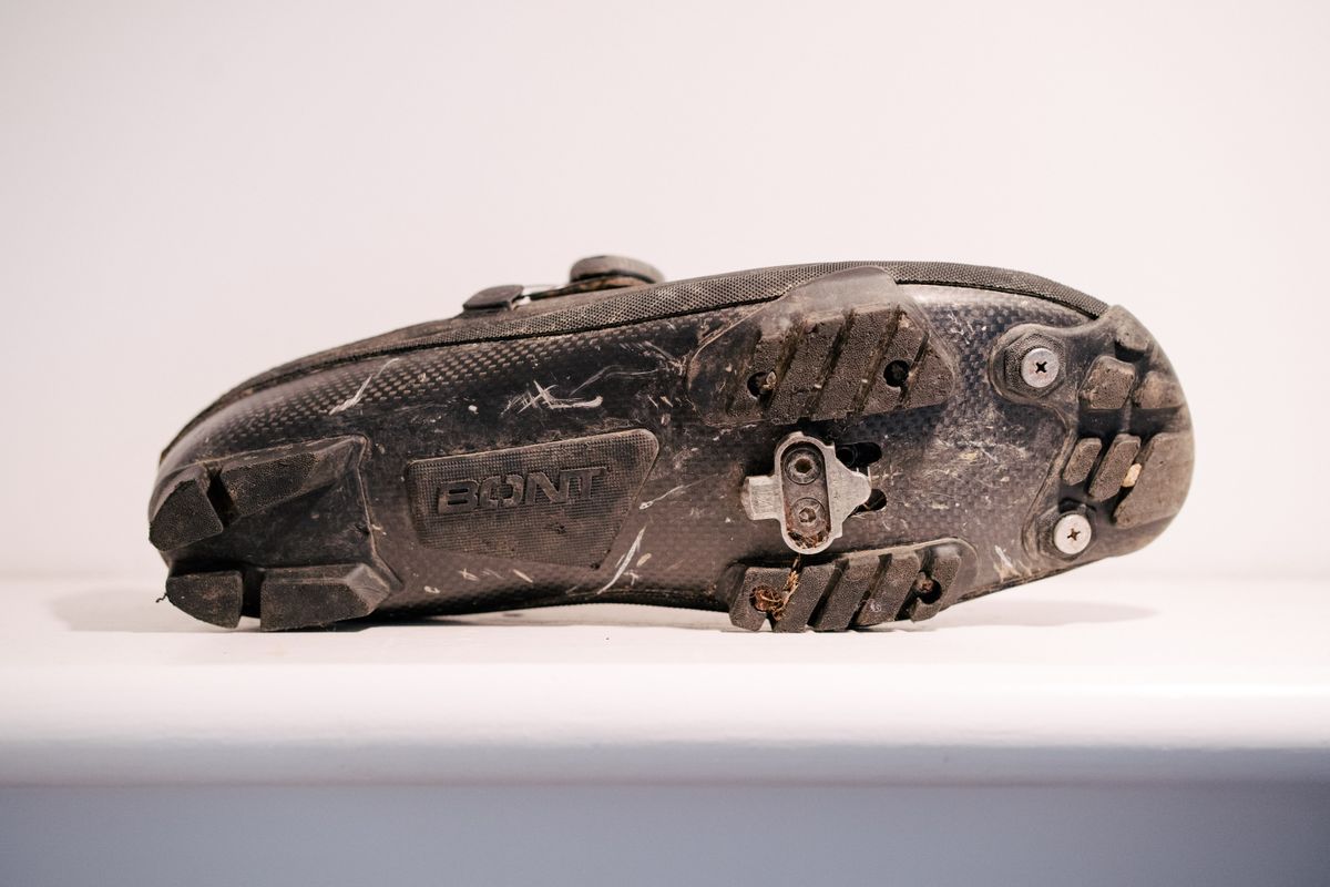 A black, muddy gravel shoe on a white shelf